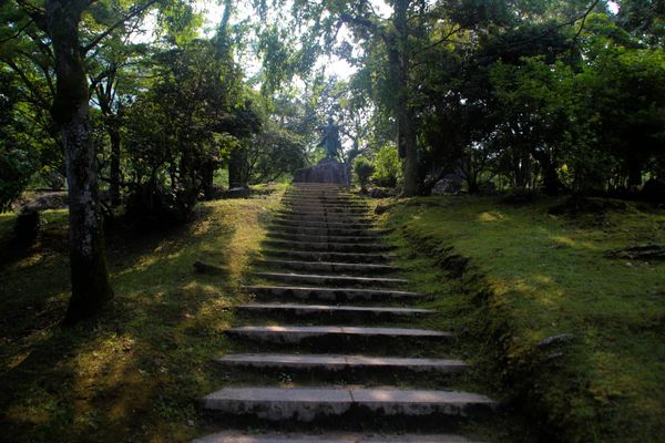stone stairs built in to the side of a hill that go up to a statue at the top, thumbnail
