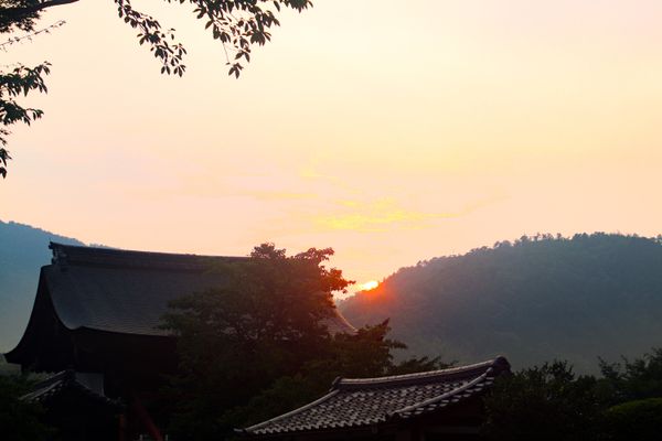 sun setting behind the mountains in the background with building in the foreground, thumbnail