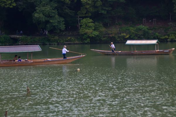 two boats passing each other being paddled by one person ferrying people across, thumbnail